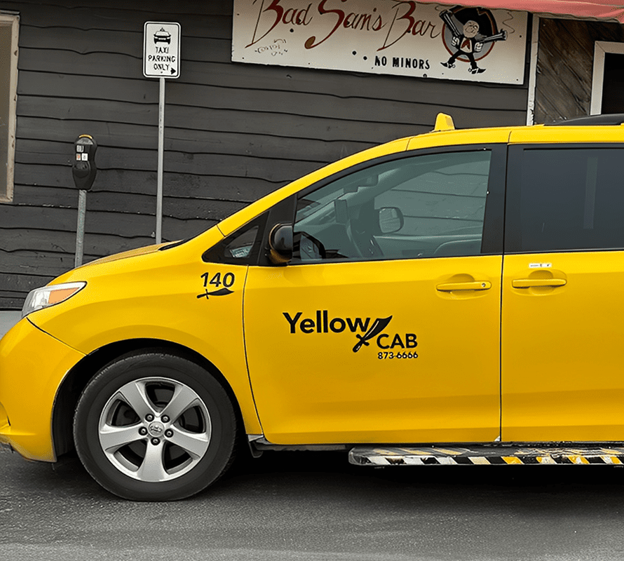 Yellow cab beside wooden building