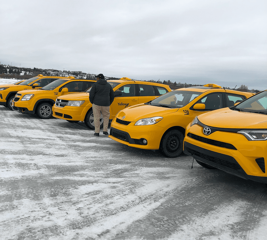Person walking by yellow taxis